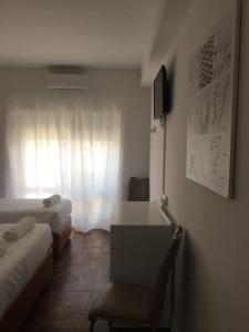 リスボンにあるLx Center Guesthouseのベッド2台、デスク、窓が備わる客室です。