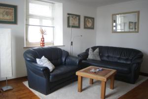 a living room with a black leather couch and a coffee table at Bei Ulla und Willi auf dem Land in Aachen