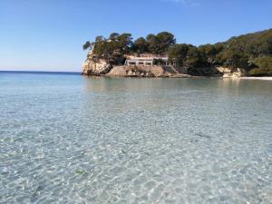 a beach with a house in the middle of the water at Cala Galdana Beach in Cala Galdana