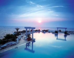 a large swimming pool with the ocean in the background at Korumar Hotel Deluxe in Kuşadası