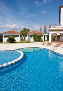 a swimming pool with blue water in front of a house at Hotel Restaurant Bon Retorn in Figueres