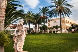 Una statua di una donna in un parco con palme di Villaggio San Giovanni a San Giorgio Ionico