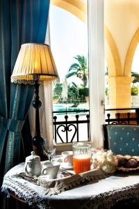 una mesa con una lámpara y un plato de comida y una ventana en Villaggio San Giovanni, en San Giorgio Ionico