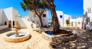 a courtyard with a tree and a fountain at Araba Fenice Village in Torre dell'Orso