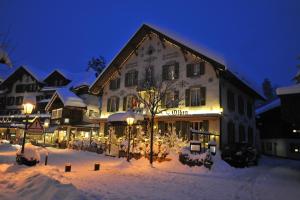 un grand bâtiment dans la neige la nuit dans l'établissement Hotel Olden, à Gstaad