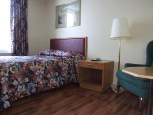 une chambre d'hôtel avec un lit, une lampe et une chaise dans l'établissement Haven Inn, à St. Anthony