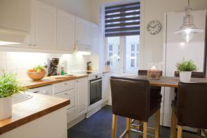 una cocina con armarios blancos y una mesa con sillas. en Vika I, As Home, en Oslo