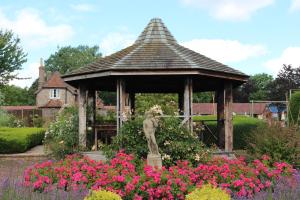 a gazebo with a statue in a garden with flowers at Garden Annex in Falfield