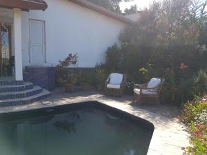 2 sillas y una piscina frente a una casa en Casa Algarrobo Chile, en Algarrobo