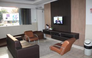 a living room with a couch and chairs and a television at Hotel Express - Leva e busca no aeroporto grátis 24 horas in Várzea Grande