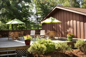 鷹河的住宿－Lake Forest Resort，一个带桌椅和遮阳伞的木制甲板