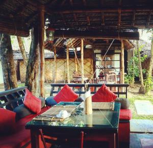 a room with a table and a couch with red pillows at Les 3 Elephants in Cherai Beach