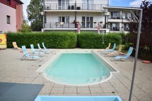 a swimming pool with chairs and a building in the background at Apartmánový Garni Hotel Relax in Senec