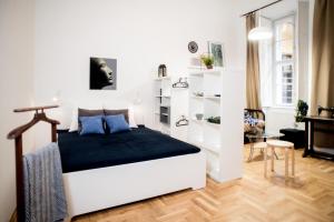 a white bedroom with a bed and a desk at City Heart Apartment in Budapest