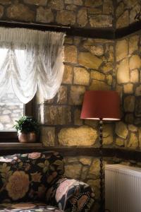 Habitación con pared de piedra, lámpara y ventana. en Archontiko Emmanouilidi Suites, en Kato Loutraki