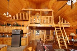 a log cabin kitchen and living room with a loft bed at Howling Wolf in Sevierville