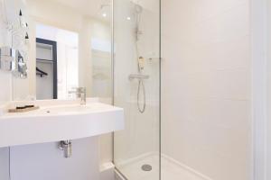 a white bathroom with a sink and a shower at Hotel Haussmann Saint Augustin in Paris