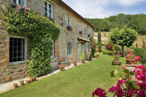 a stone building with a yard with flowers at Villa Petrognano in Petrognano