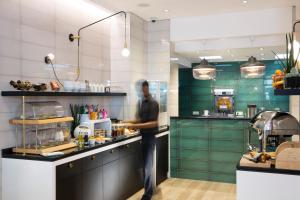 a man standing in a kitchen preparing food at Hotel Haussmann Saint Augustin in Paris