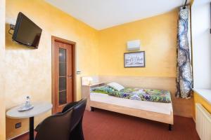 um pequeno quarto com uma cama e uma televisão em Hotel Conti em Olomouc