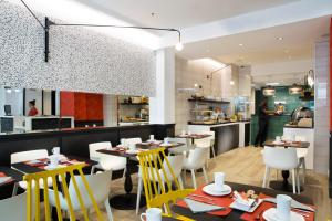 a restaurant with tables and chairs and a kitchen at Hotel Haussmann Saint Augustin in Paris