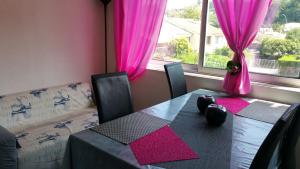 uma sala de jantar com uma mesa e cortinas cor-de-rosa em Résidence Cap Azur Appartement 217 em Villeneuve-Loubet