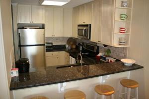 a kitchen with a stainless steel refrigerator and wooden stools at Next 2 Paradise-203 in Holden Beach