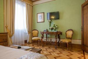a bedroom with a table with two chairs and a television at Due Torri Hotel in Verona
