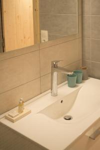 a bathroom sink with a faucet and two cups on it at La ferme des Colieuvres in Lièpvre