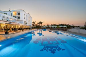 a large swimming pool with a hotel in the background at Dona Filipa Hotel in Vale do Lobo