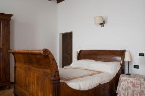 um quarto com uma cama de madeira antiga com lençóis brancos em Palazzo Turro Bed & Breakfast em Podenzano