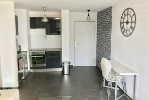 eine Küche mit einem Tisch und Stühlen sowie einer Uhr an der Wand in der Unterkunft Le T2 Appartement Moderne avec Terrasse et Parking in Straßburg