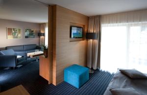 a living room with a couch and a blue stool at Hotel-Restaurant Ammerhauser in Anthering