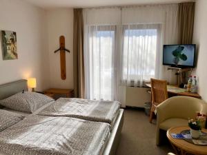 Hotel Del Sol في باد فيلدونجين: غرفة نوم مع سرير ومكتب مع جهاز كمبيوتر