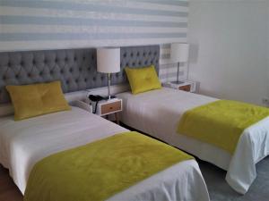 two beds in a hotel room with yellow pillows at Ansiturismo Alojamento in Ansião