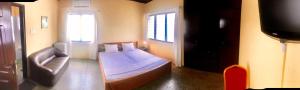 a bedroom with a bed and a chair and a television at Royal German Guest House in Ablekuma