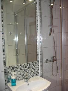 een badkamer met een wastafel en een douche met een spiegel bij Studio Aleja 77 in Częstochowa