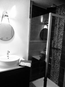 La salle de bains en noir et blanc est pourvue d'un lavabo et d'une douche. dans l'établissement Les Gîtes de Laure - L'Or Vert, Appartement avec Vue sur le Château, Parking Privé, Climatisation, Netflix, à 160 m de la Cité Médiévale, à Carcassonne