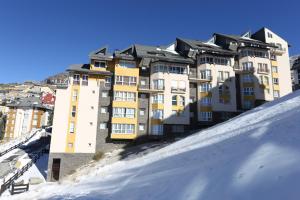 un gran edificio en la cima de una colina nevada en Miramar Ski a pie de pista - ÁTICO DUPLEX , 4 habitaciones en Sierra Nevada