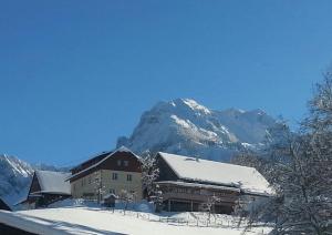 a building covered in snow with a mountain in the background at Singerskogel in Spital am Pyhrn
