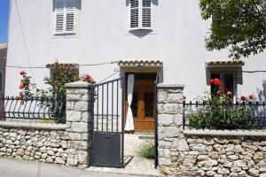 a white house with a gate and a stone fence at Apartments Gabri in Mali Lošinj