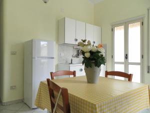Una cocina con una mesa con un jarrón de flores encima. en Residence Santa Barbara, en San Ferdinando