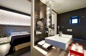a bathroom with a tub, sink, and mirror at Vincci Vía - 66 in Madrid