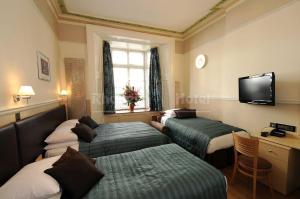 a hotel room with three beds and a flat screen tv at Rhodes Hotel in London