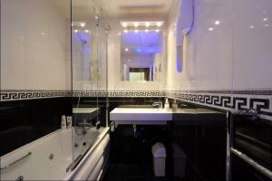 ein Badezimmer mit einer Badewanne, einem Waschbecken und einem Spiegel in der Unterkunft Rhodes Hotel in London