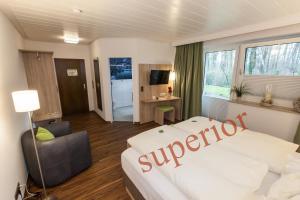 ein Schlafzimmer mit einem großen weißen Bett und einem Stuhl in der Unterkunft Hotel am Springhorstsee in Großburgwedel