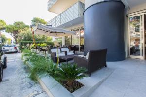 un patio con sillas y una sombrilla frente a un edificio en Nautilus, en Riccione