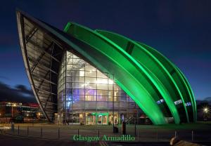 a large building with a green facade at night at Glasgow City Centre Apartment in Glasgow