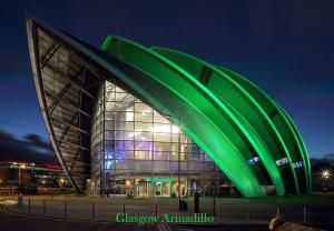 a large building with a green facade at night at Glasgow City Centre Apartment in Glasgow