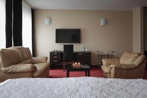 a living room with two chairs and a flat screen tv at Hotel Palma in Mažeikiai